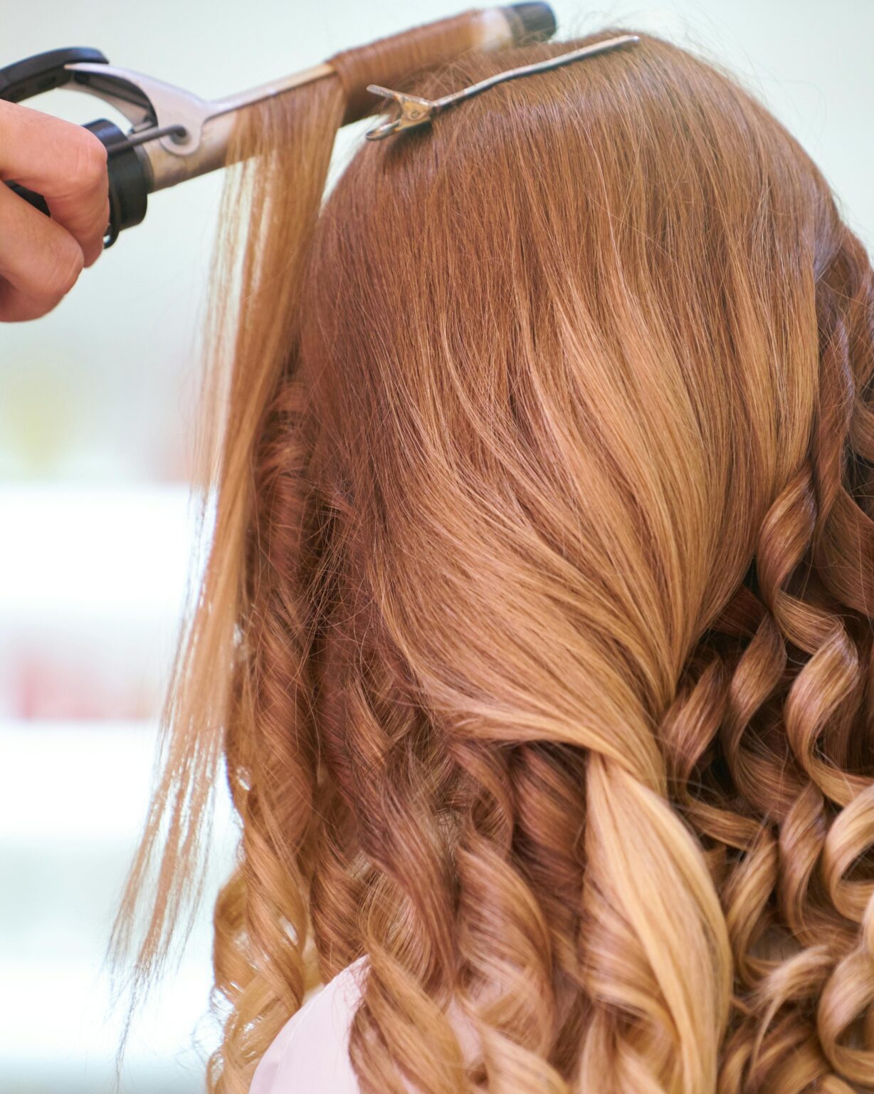 Image of a red-headed woman having her hair styled.